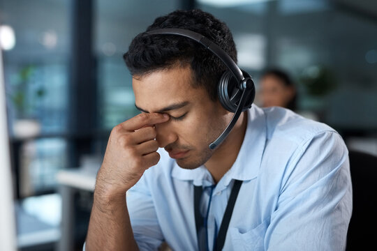 Help yourself before you help others. Shot of a young man using a headset and looking stressed in a modern office.