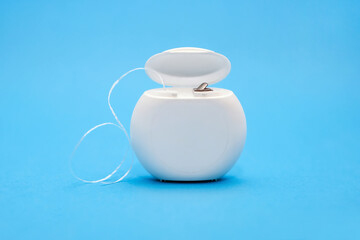 Dental floss for cleaning teeth on a blue background. The concept of oral care and caries prevention. Dental care products and oral hygiene