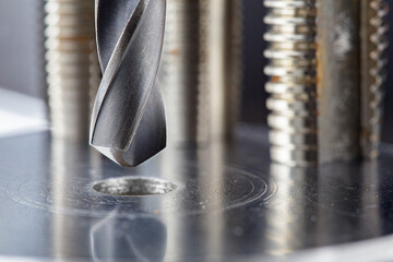 metal drill bit make holes in steel billet with tech oil on industrial drilling machine. Metal work...