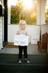 child holds a first day of preschool sign