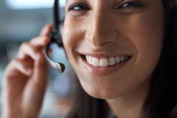 The bigger the smile, the better the service. Portrait of a young woman using a headset in a modern...