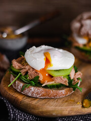 Poached egg on a full grain bun with avocado, cucumber, kiwi and arugula on a gray plate. Healthy breakfast. Brunch idea. Clean eating. vegetarian. protein source food