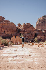 Tourist man with a backpack exploring the sights of the ancient, fabulous city of Petra in Jordan. Colorful photos. Vacation, vacation and travel concept