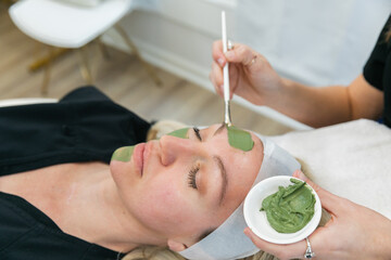 Woman applying a green tea skin care facial at a local spa