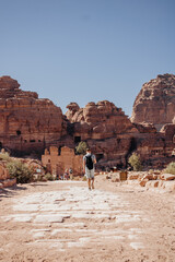 Tourist man with a backpack exploring the sights of the ancient, fabulous city of Petra in Jordan. Colorful photos. Vacation, vacation and travel concept