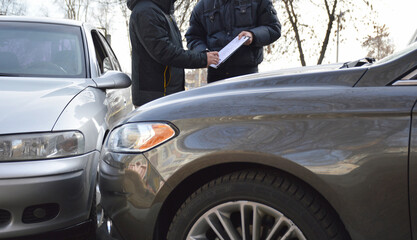Two men sign a car accident report for an insurance claim. the concept of road safety and receiving insurance payments