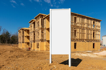 New Apartment Construction Framework With Blank White Sign In Foreground