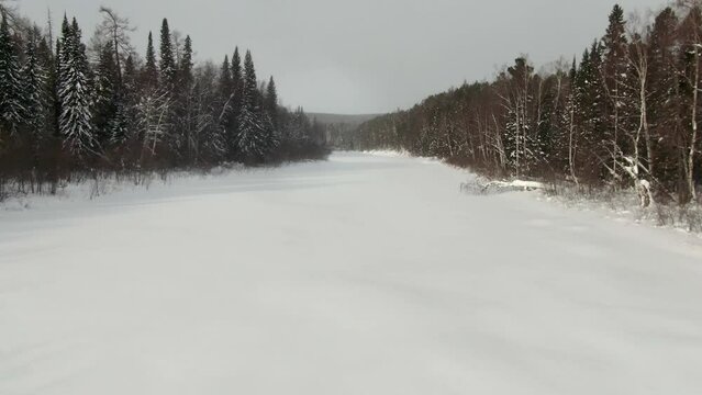 Drone flying over the frozen river Lozva, low flight, smooth rise, the road to the Dyatlov Pass