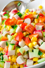 salad of cucumbers, corn, bell peppers and crab sticks. Close-up, vertical photo.