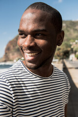 Close up african american man in striped teeshirt smiling and looking away