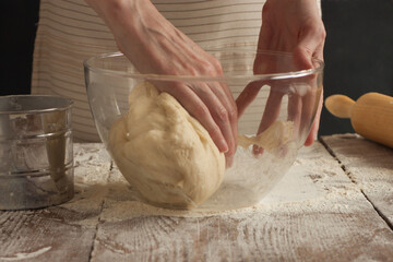 A woman kneads the dough with her hands