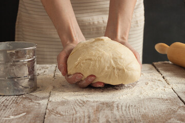 A woman holds a dough in her hands