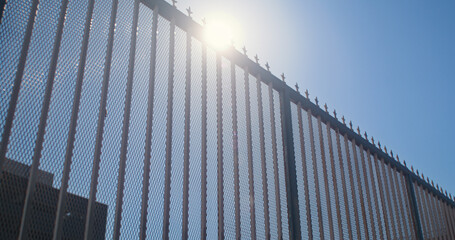 Modern city fence on sunlight bottom view. Metal barrier against city background