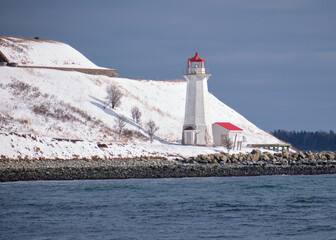  Lighthouse covered in snow on sunny winter day. - obrazy, fototapety, plakaty
