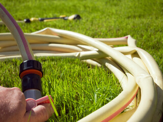 Watering lawn grass. Hand turns on a faucet for watering the lawn with a connected hose
