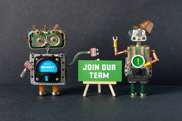 Join our team. Job search recruitment concept. Two HR robots recruit employees, offer vacancies, look for workers. Big green poster on wooden easel, black background - 485891683