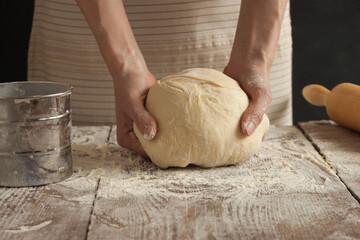 A woman holds a dough in her hands