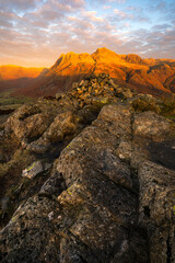 Golden light at sunrise illuminating the peaks of The Langdale Pikes in The Lake District, UK.