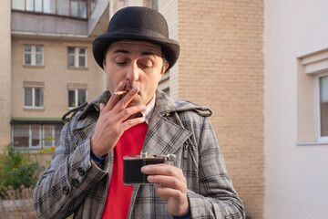 Portrait of a man smoking a cigarette with alcohol in his hands outdoors on a sunny day....