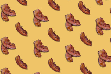 Pattern made lot of crispy bacon slices on yellow background.