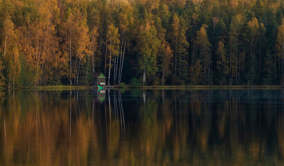 fishing shelter in autumn evening on the forest lake