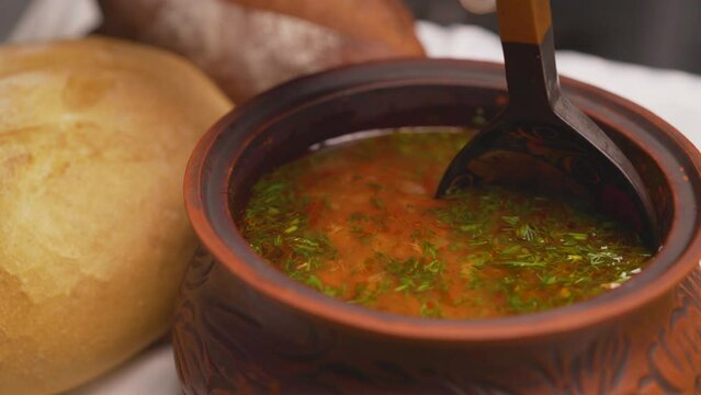 Cooking homemade soup. The chef stirs the freshly prepared soup with a wooden spoon.