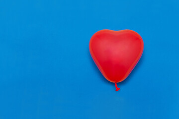 Fototapeta na wymiar A balloon in the form of a red heart on a blue background. Valentine's day. Love.