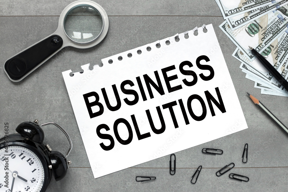 Poster clock, money on a gray background near white paper from a notepad with text business solution