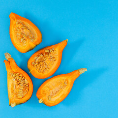 Sliced pieces of organic pumpkin on cyan or blue background. MInimal autumn food layout. Flat lay