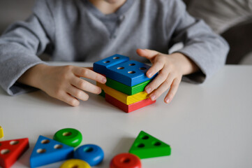 A child is playing with a colored educational wooden toy. Children's Wooden Toy