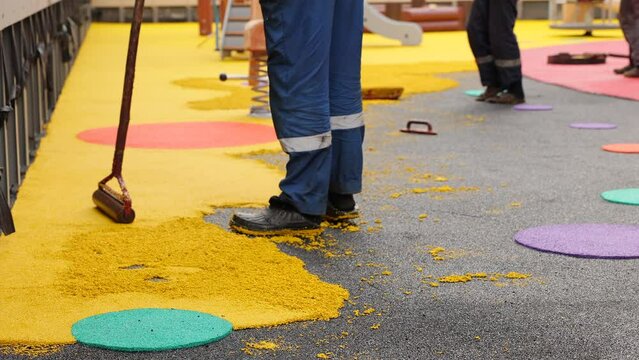 Rubber coating for playgrounds applied on the surface by a steel roller tools. PDM rubber granules. Floor covering for sports. Rubber mulch for safety and injury prevention. Selective focus.