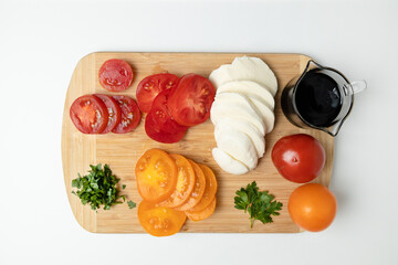 Assorted fresh organic tomato vegetables on wooden board on a white background for healthy salad. Top view
