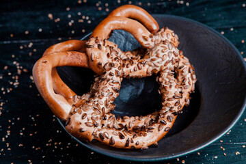 Fresh prepared homemade soft pretzels. Different types of baked bagels with seeds on a black background.