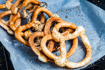 Fresh prepared homemade soft pretzels. Different types of baked bagels with seeds on a black background.