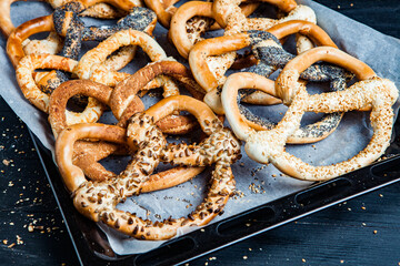 Fresh prepared homemade soft pretzels. Different types of baked bagels with seeds on a black background.