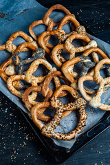 Fresh prepared homemade soft pretzels. Different types of baked bagels with seeds on a black background.