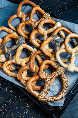 Fresh prepared homemade soft pretzels. Different types of baked bagels with seeds on a black background.