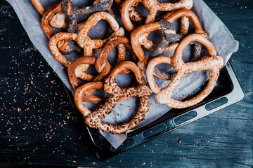 Fresh prepared homemade soft pretzels. Different types of baked bagels with seeds on a black background.