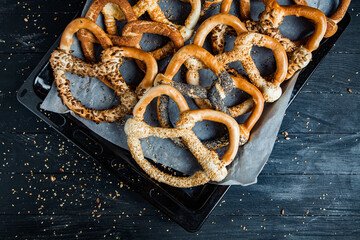 Fresh prepared homemade soft pretzels. Different types of baked bagels with seeds on a black background.