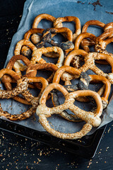 Fresh prepared homemade soft pretzels. Different types of baked bagels with seeds on a black background.