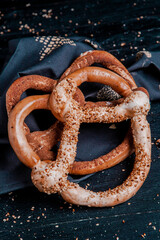 Fresh prepared homemade soft pretzels. Different types of baked bagels with seeds on a black background.
