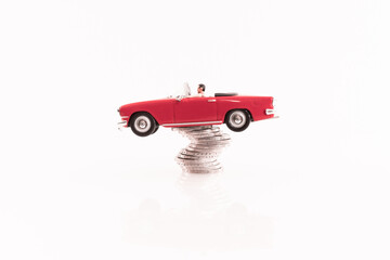 Véhicule miniature cabriolet rouge avec des pièces de monnaie.	