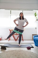 Obraz premium Chica joven guapa haciendo ejercicio en mallas grises en el salón de su casa