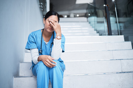 Sometimes not everything is in our hands. Shot of a female nurse looking stressed while sitting on a staircase.