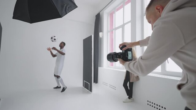 A sporty black male model poses for advertising posters. He plays with the Ball for spectacular shots. Stylish Fashionable Sports Magazine. A photo shoot made with professional equipment in the studio