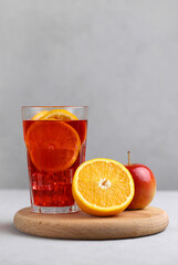 Homemade sangria drink with fruits: apple, orange, lemon and ice cubes on a gray background. Selective focus. Vertical photo.