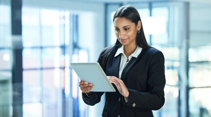 Im sending you those emails now. Shot of a young businesswoman using a digital tablet at work.