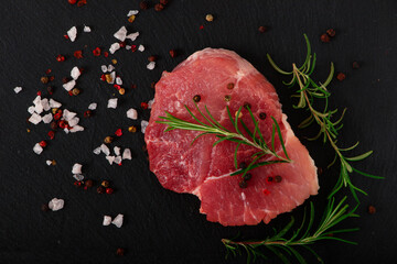Fresh steak with herbs and spices at black background.
