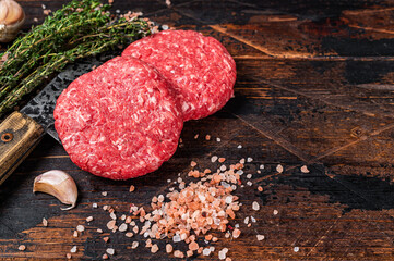 Raw steak cutlets with mince beef meat on a butcher cleaver. Wooden background. Top view. Copy space