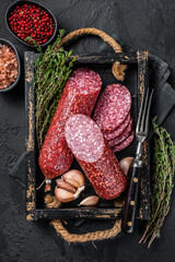 Sliced Dry salami sausage with fresh thyme. Black background. Top view